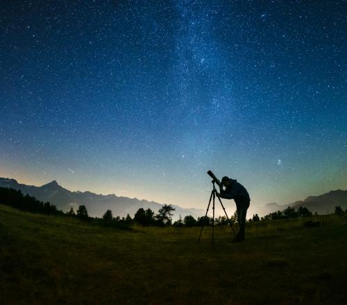 Sterngucker Peter Salzmann schaut durch ein Fernrohr in den Nachthimmel.