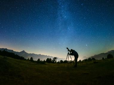 Sterngucker Peter Salzmann schaut durch ein Fernrohr in den Nachthimmel.